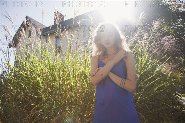 Woman standing near tall plants in backyard