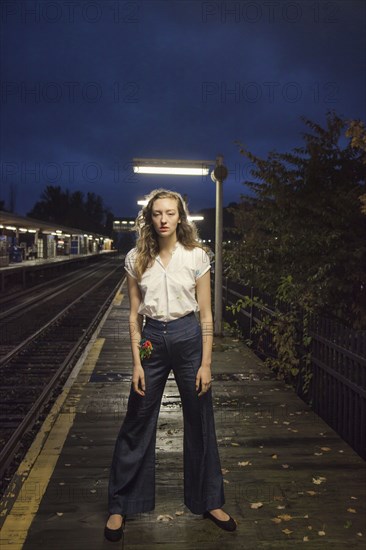 Woman waiting for train at train station at night