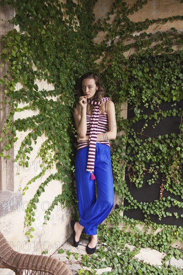 Woman leaning on ivy wall