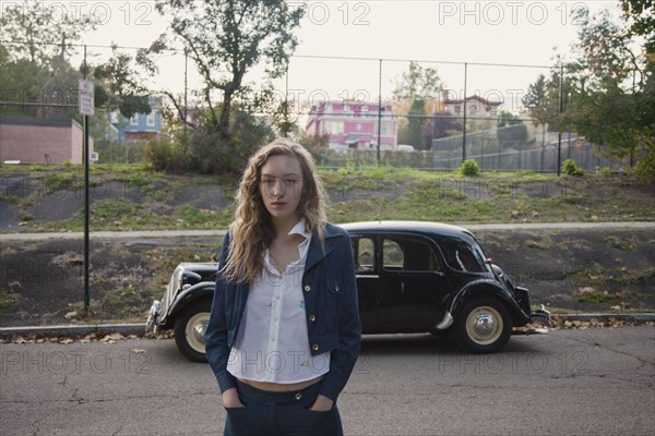 Woman crossing city street near classic car