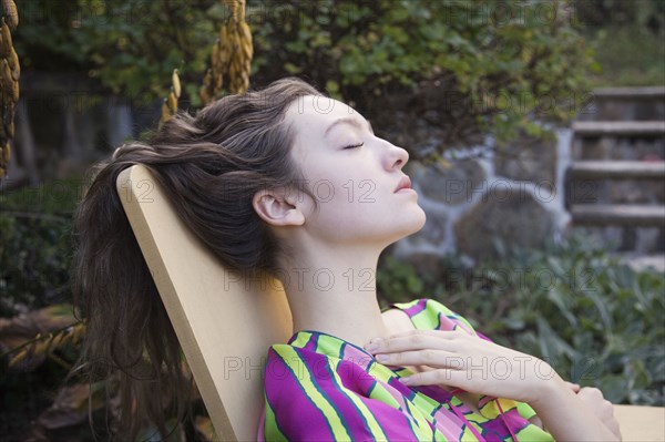 Woman relaxing in lawn chair in backyard