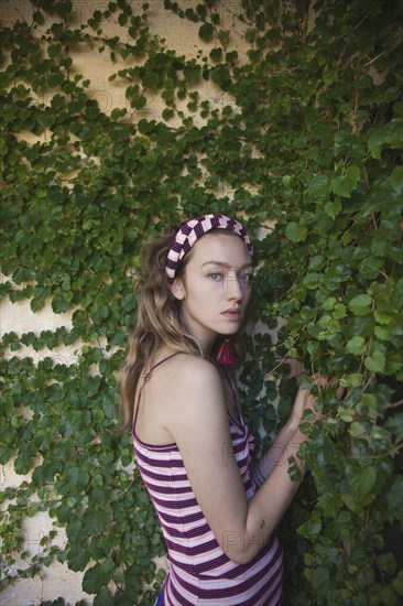 Woman standing at ivy wall