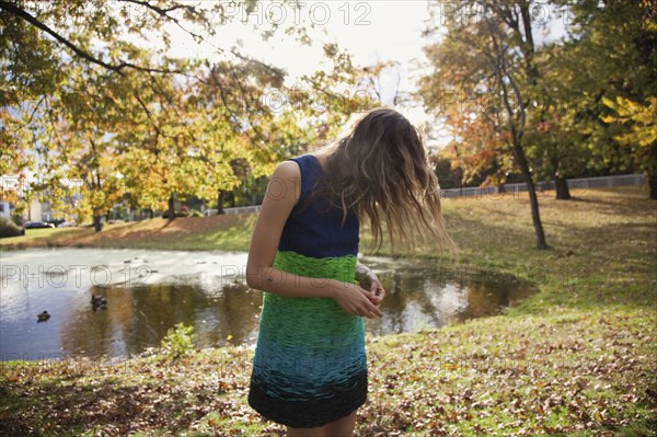 Hair hiding face of woman near duck pond in park