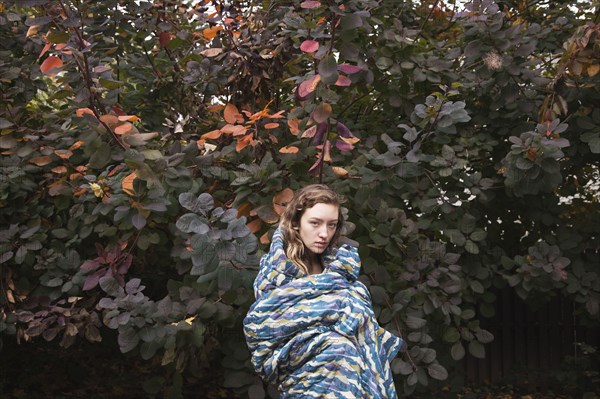 Woman wrapped in blanket near tree