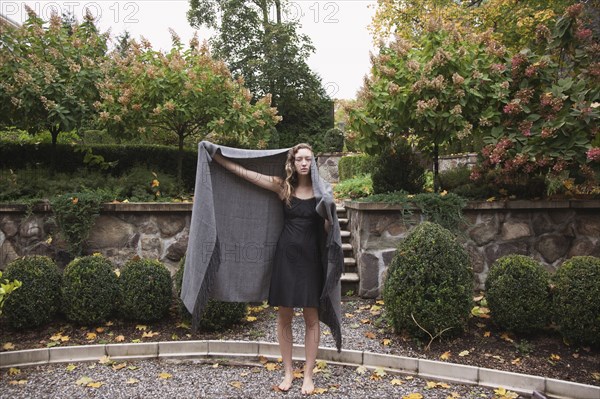 Woman holding blanket standing in courtyard