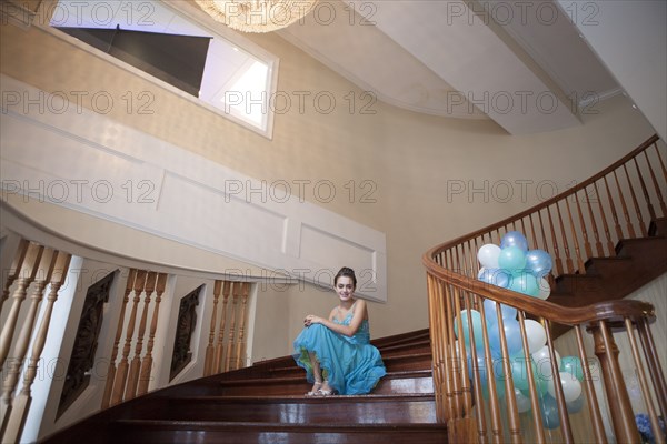 Caucasian teenage girl wearing formal dress on steps