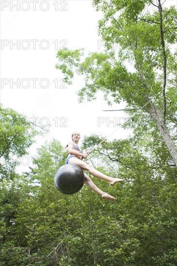 Teenage girl swinging on rope swing