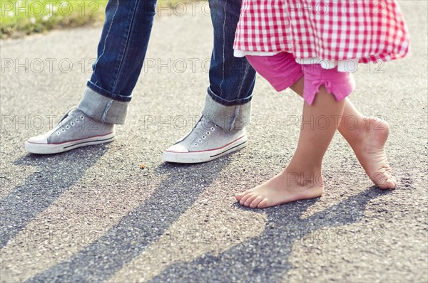 Children barefoot and with sneakers standing on concrete