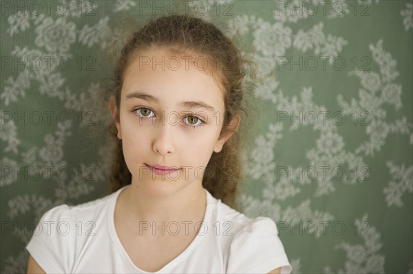Close up of somber Caucasian girl near wallpaper