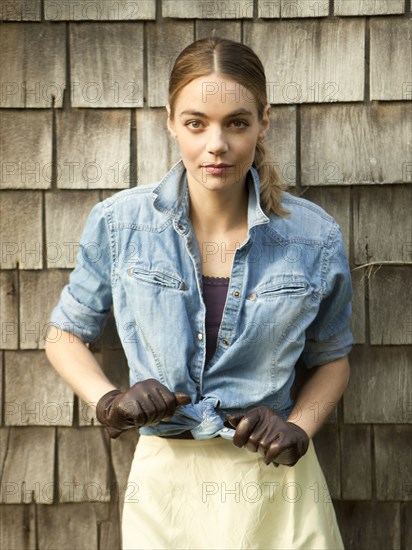 Woman tying her shirt near wooden shingles