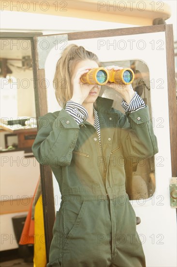 Woman looking through binoculars on boat deck