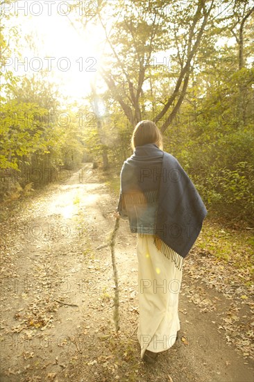 Woman walking on dirt path in forest