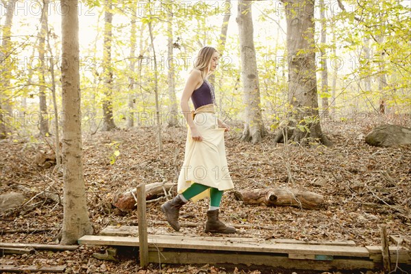 Woman walking on wooden walkway in forest