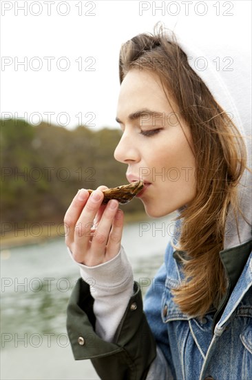 Woman eating fresh oyster at lake