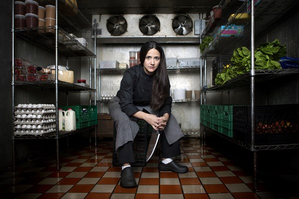 Chef sitting in walk-in refrigerator in restaurant