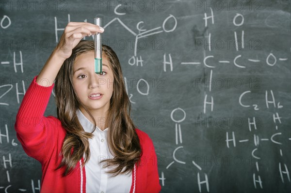 Hispanic student examining test tube in science class