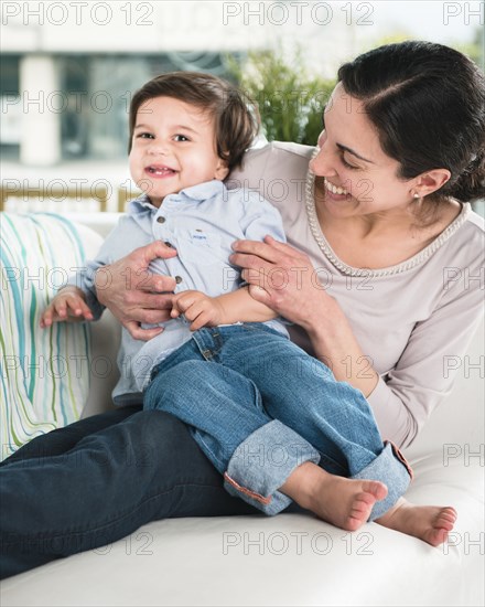 Smiling mother tickling son on sofa