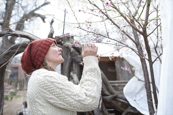 Woman admiring flowering tree branches in garden