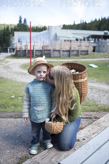 Mother with long hair kissing son in park