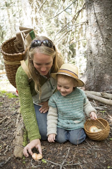 Mother and son foraging for mushrooms in forest