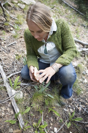 Woman foraging for mushrooms in forest
