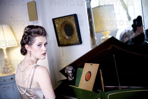 Woman sitting at piano in ornate living room