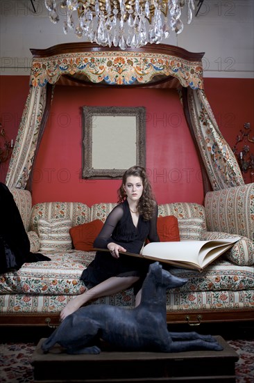 Woman reading oversized book on sofa in ornate living room