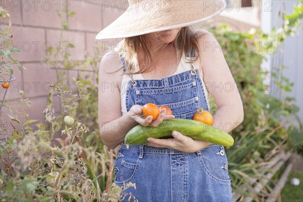 Mixed race farmer gathering vegetables in garden