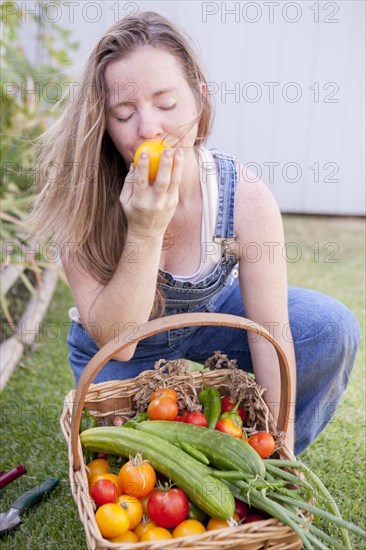 Mixed race farmer smelling vegetables in garden
