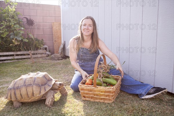 Mixed race farmer and tortoise basket of vegetables