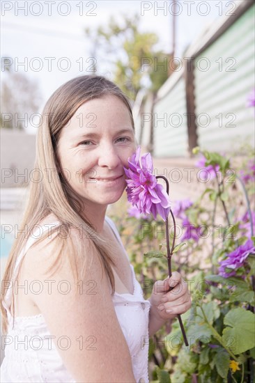 Mixed race woman smelling flowers in garden