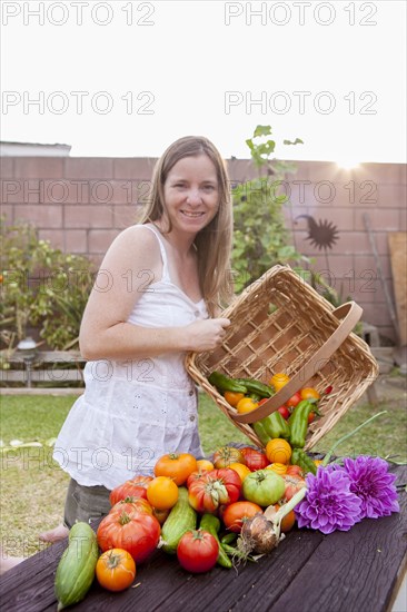 Mixed race woman with basket of vegetables and flowers