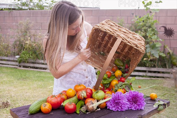 Mixed race woman with basket of vegetables and flowers