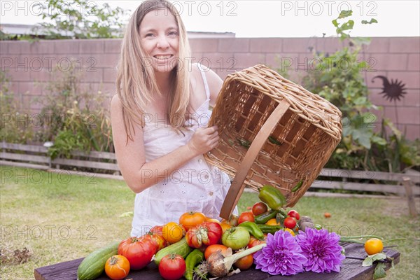 Mixed race woman with basket of vegetables and flowers