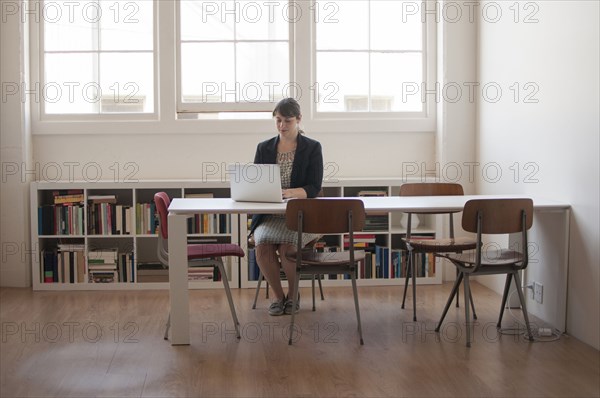 Caucasian businesswoman working on laptop in office