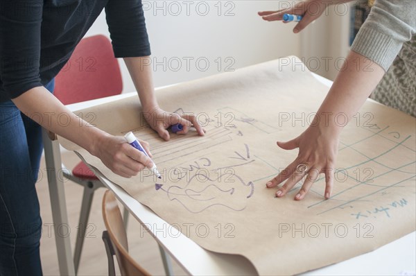 Businesswomen sketching diagram in office