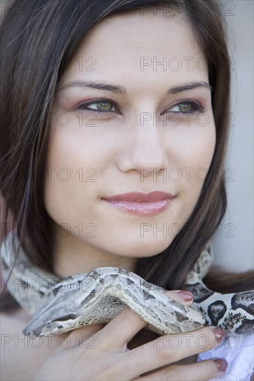 Close up of Hispanic woman with snake around her neck