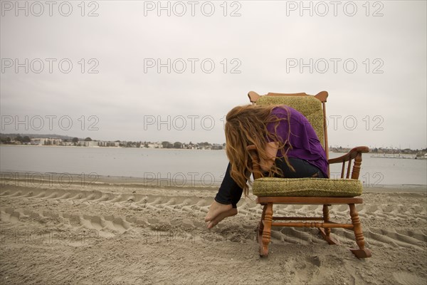 Woman sitting in armchair on beach