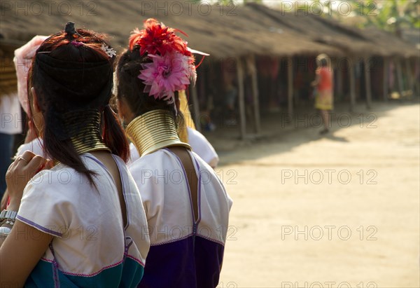 Students wearing traditional jewelry near huts
