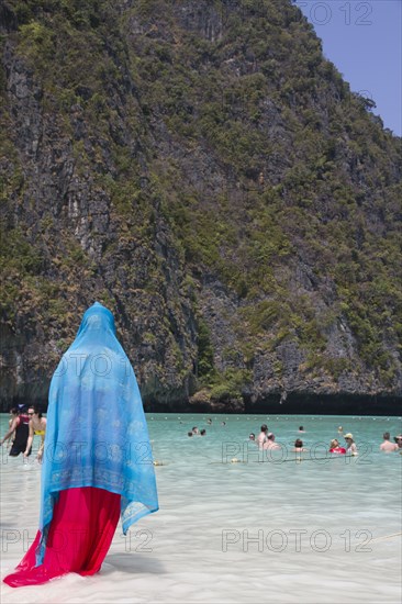 Woman in traditional headscarf standing on beach