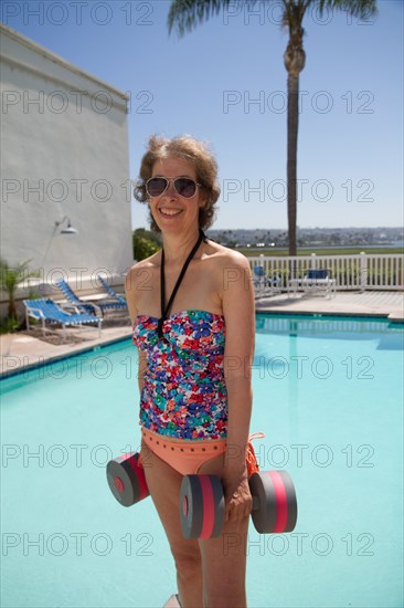 Caucasian woman holding dumbbells by swimming pool