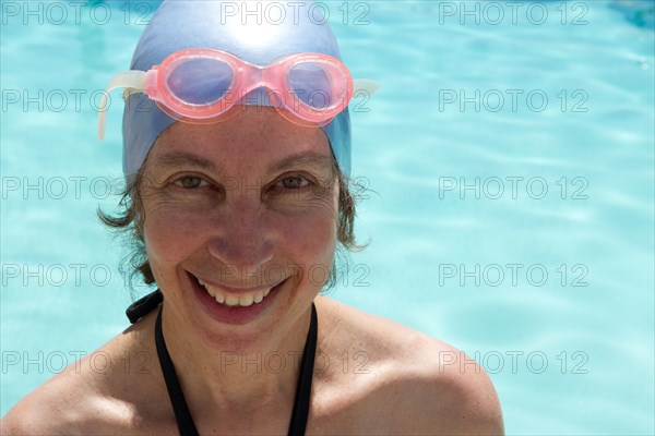 Caucasian woman in goggles and swim cap by swimming pool