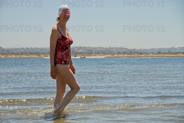 Caucasian woman walking in waves on beach