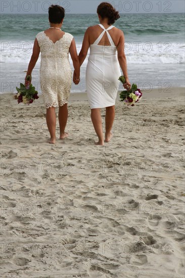 Lesbian brides holding hands on beach