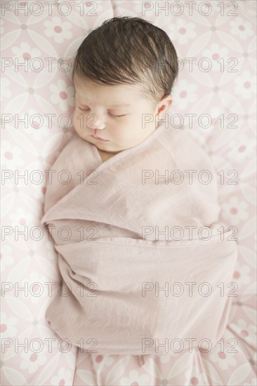 Caucasian baby girl swaddled in blanket