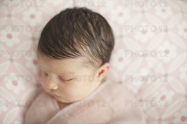 Caucasian baby girl swaddled in blanket