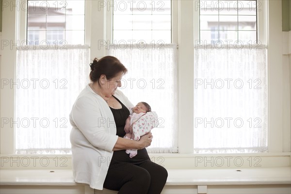 Caucasian woman holding baby granddaughter in windowsill