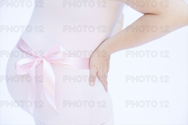 Pregnant Caucasian woman with pink ribbon around belly
