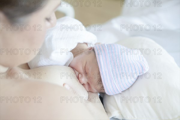 Caucasian mother nursing newborn daughter in hospital bed