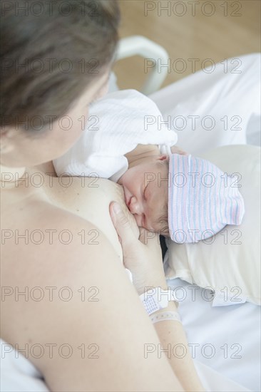 Caucasian mother nursing newborn daughter in hospital bed